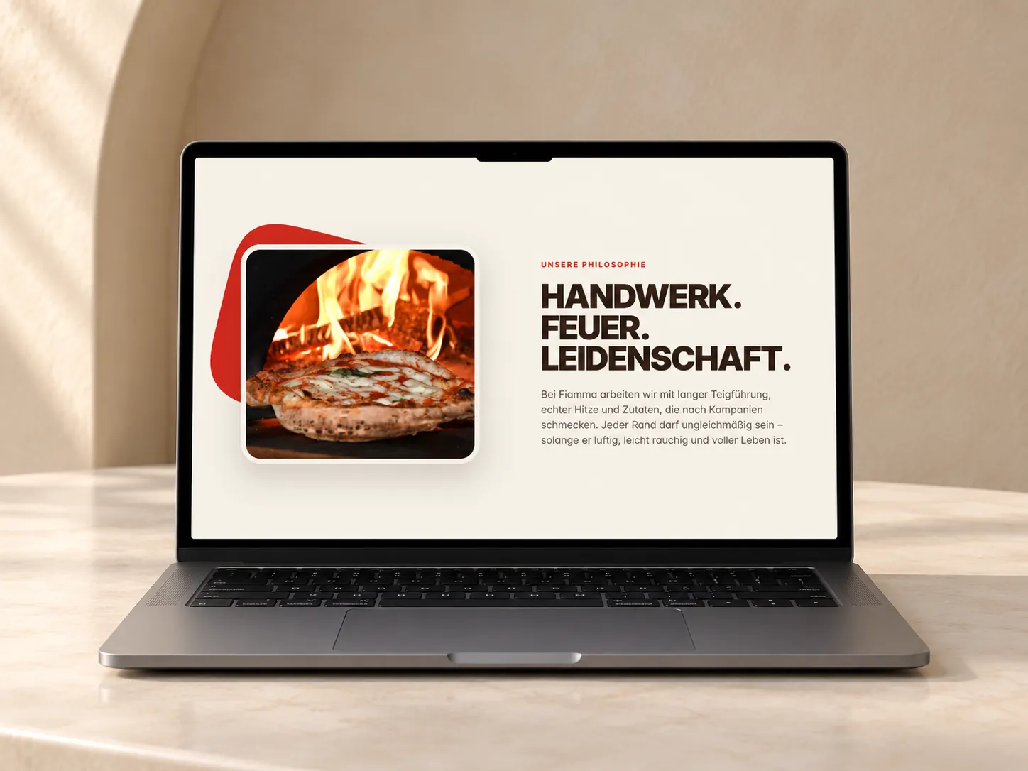 Laptop, auf dem Bildschirm der Abschnitt Unsere Philosophie: Handwerk. Feuer. Leidenschaft. neben einer Pizza im Holzofen