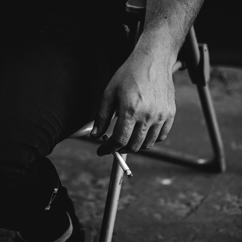 Schwarzweißaufnahme einer Hand an einer Stuhllehne